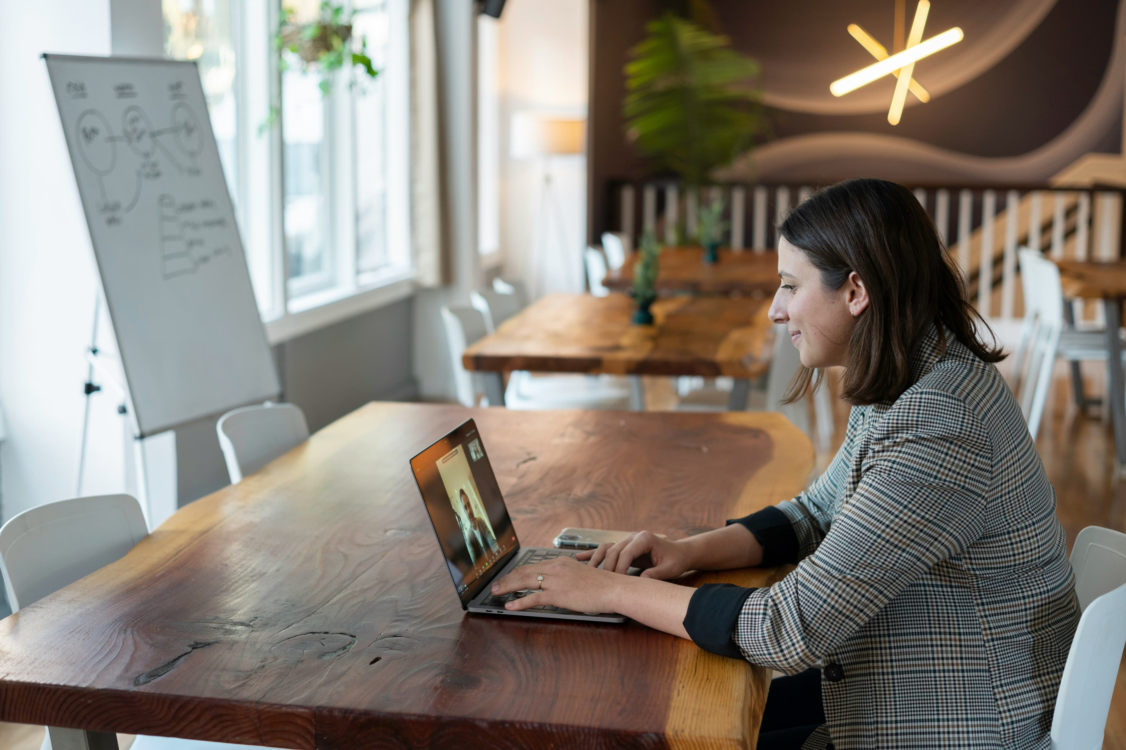 A woman on a video call at a laptop in a bright open workspace